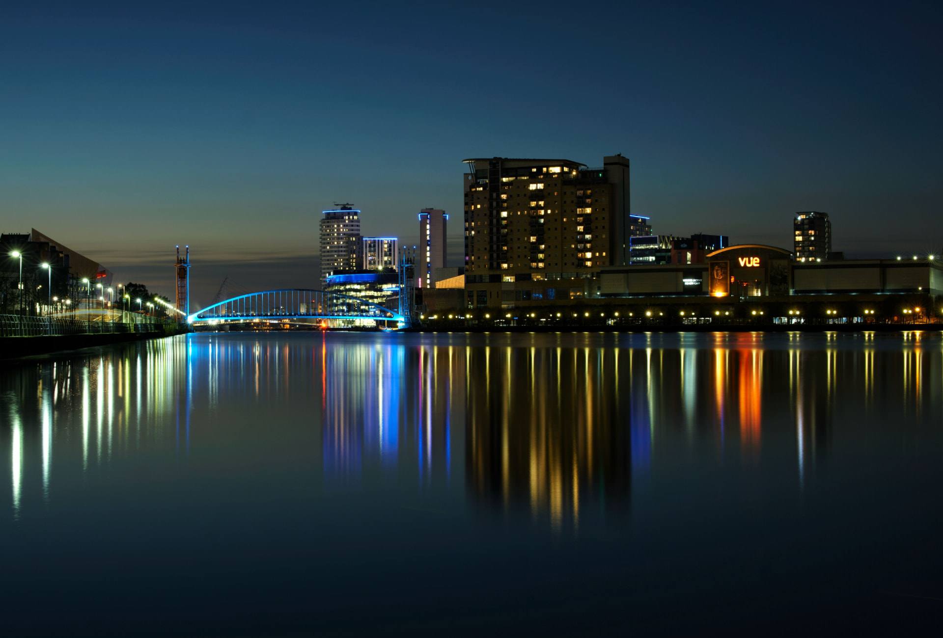 Manchester's Salford Quays waterfront at night, city lights reflecting on the water